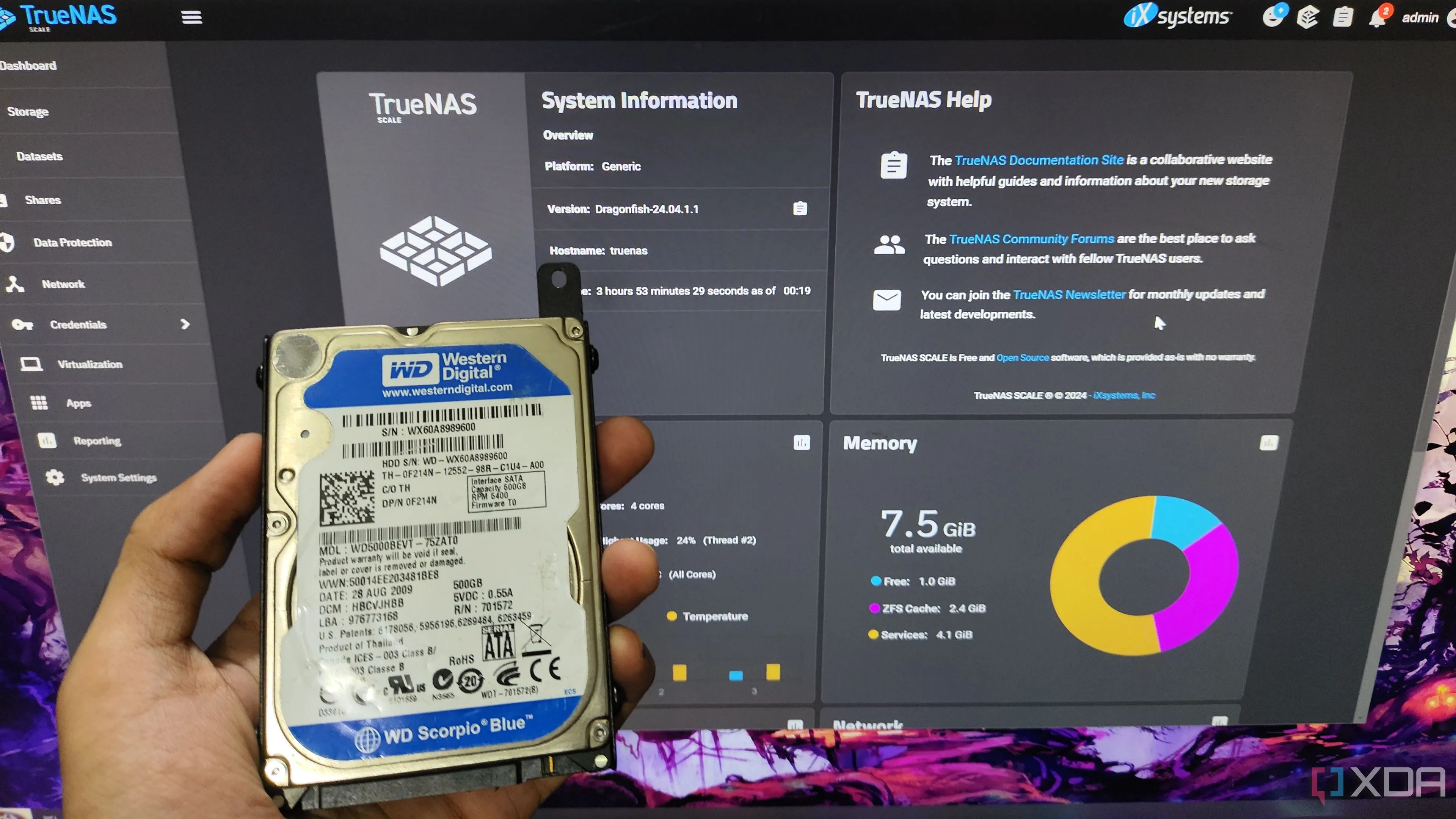 Một người dùng đang cầm ổ cứng HDD trước màn hình giao diện web của TrueNAS Scale, minh họa cho việc tự xây dựng hệ thống NAS