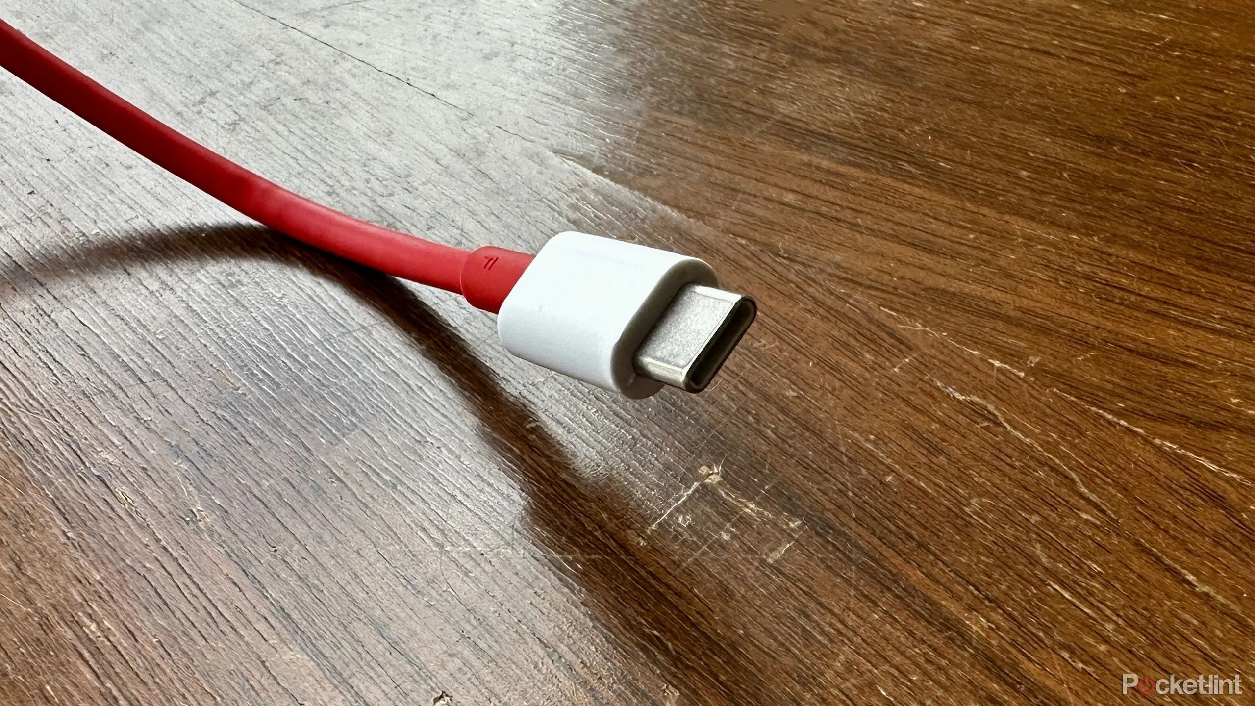 Sợi cáp USB-C màu đỏ đặt trên mặt gỗ cũ.