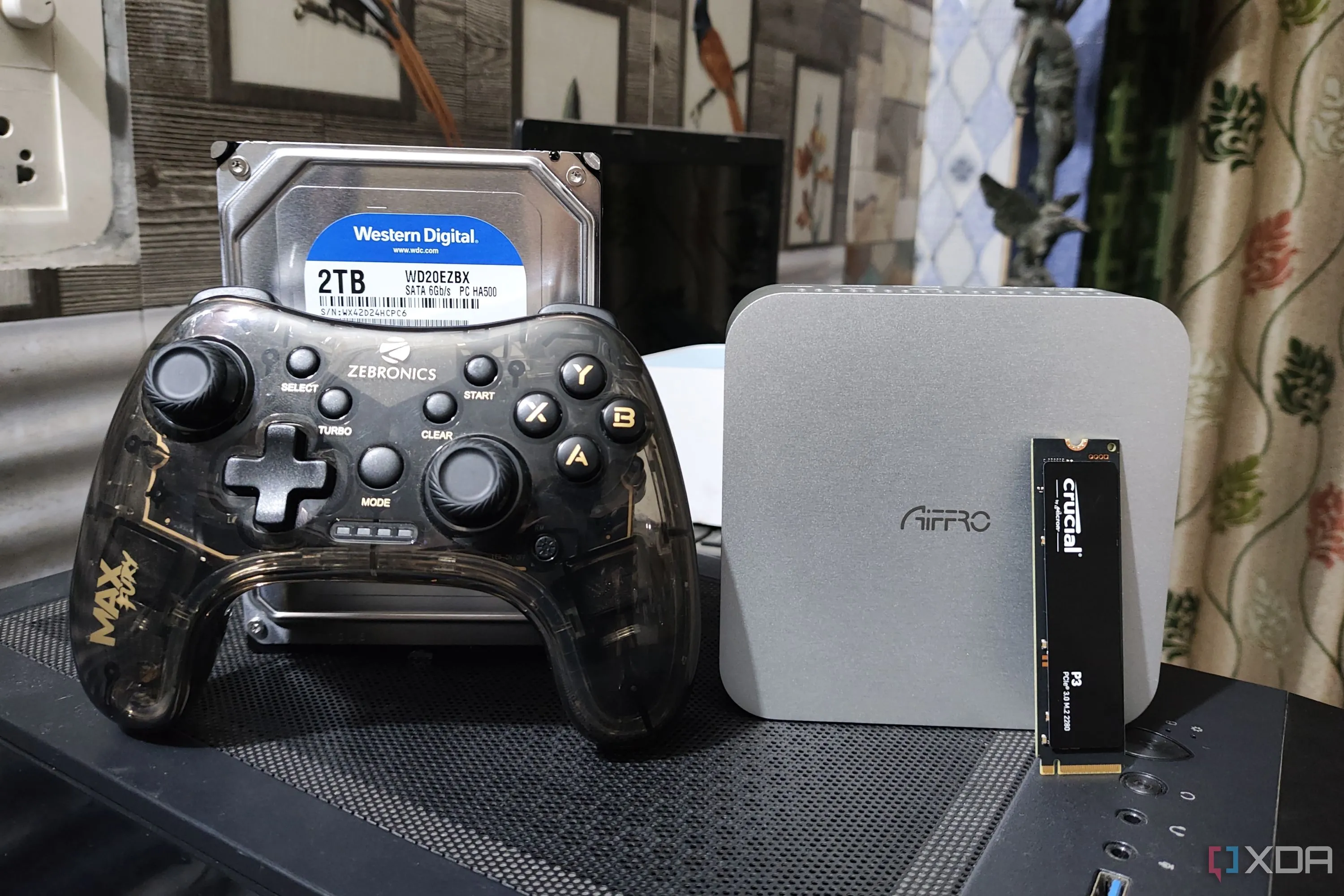 Thiết bị NAS Aiffro K100 cùng tay cầm chơi game, ổ cứng HDD và SSD, minh họa việc sử dụng NAS cho mục đích lưu trữ game