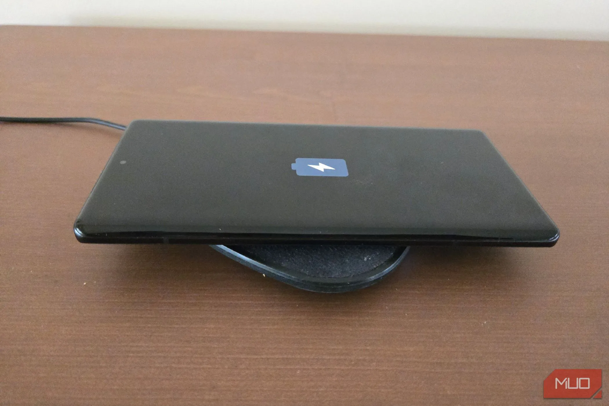 Điện thoại Motorola Edge Plus 2023 đang được đặt trên đế sạc không dây, minh họa hành động sạc pin.