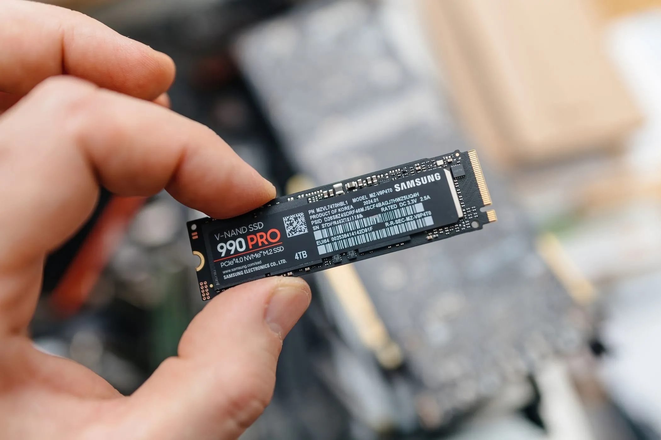 Một người đàn ông đang cầm trên tay ổ cứng SSD Samsung 990 Pro, minh họa kích thước nhỏ gọn của ổ NVMe M.2