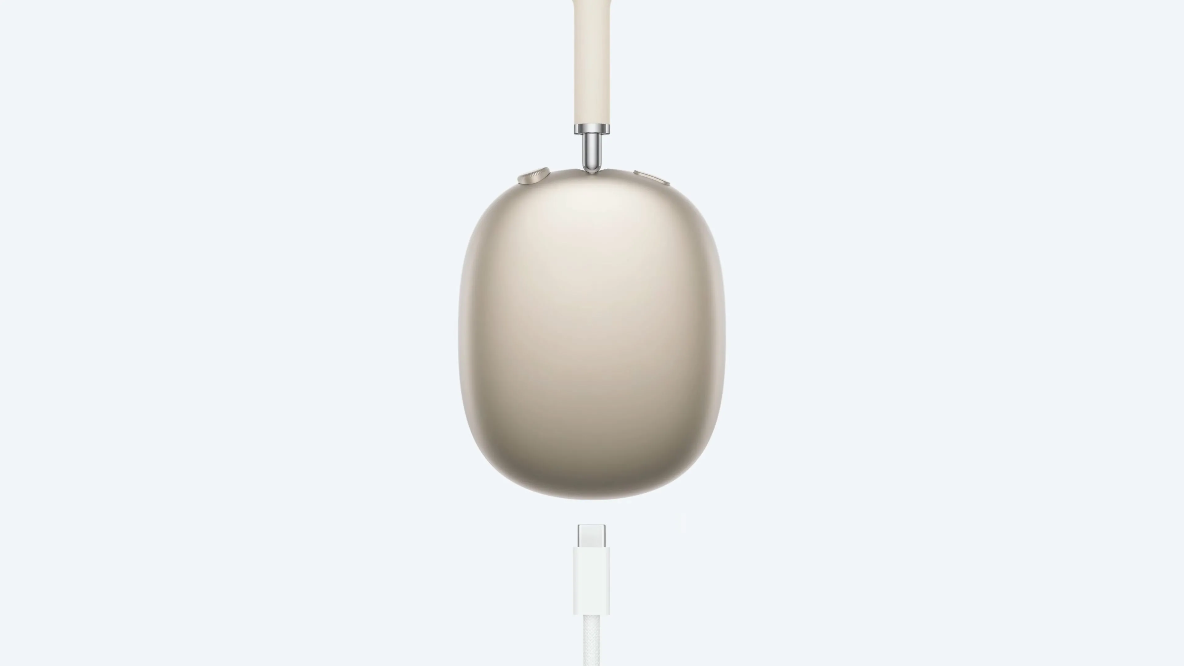 AirPods Max màu Starlight đang được sạc qua cổng USB-C, làm nổi bật vấn đề không thể sử dụng tai nghe trong khi sạc.