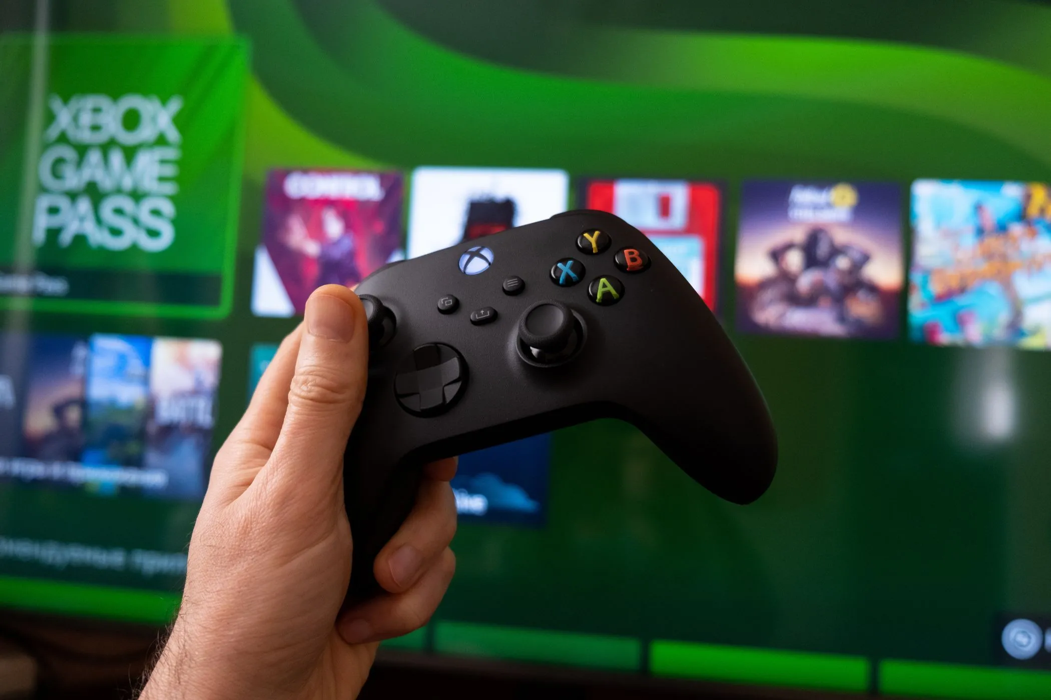 an xbox controller with xbox game pass on a screen in the background