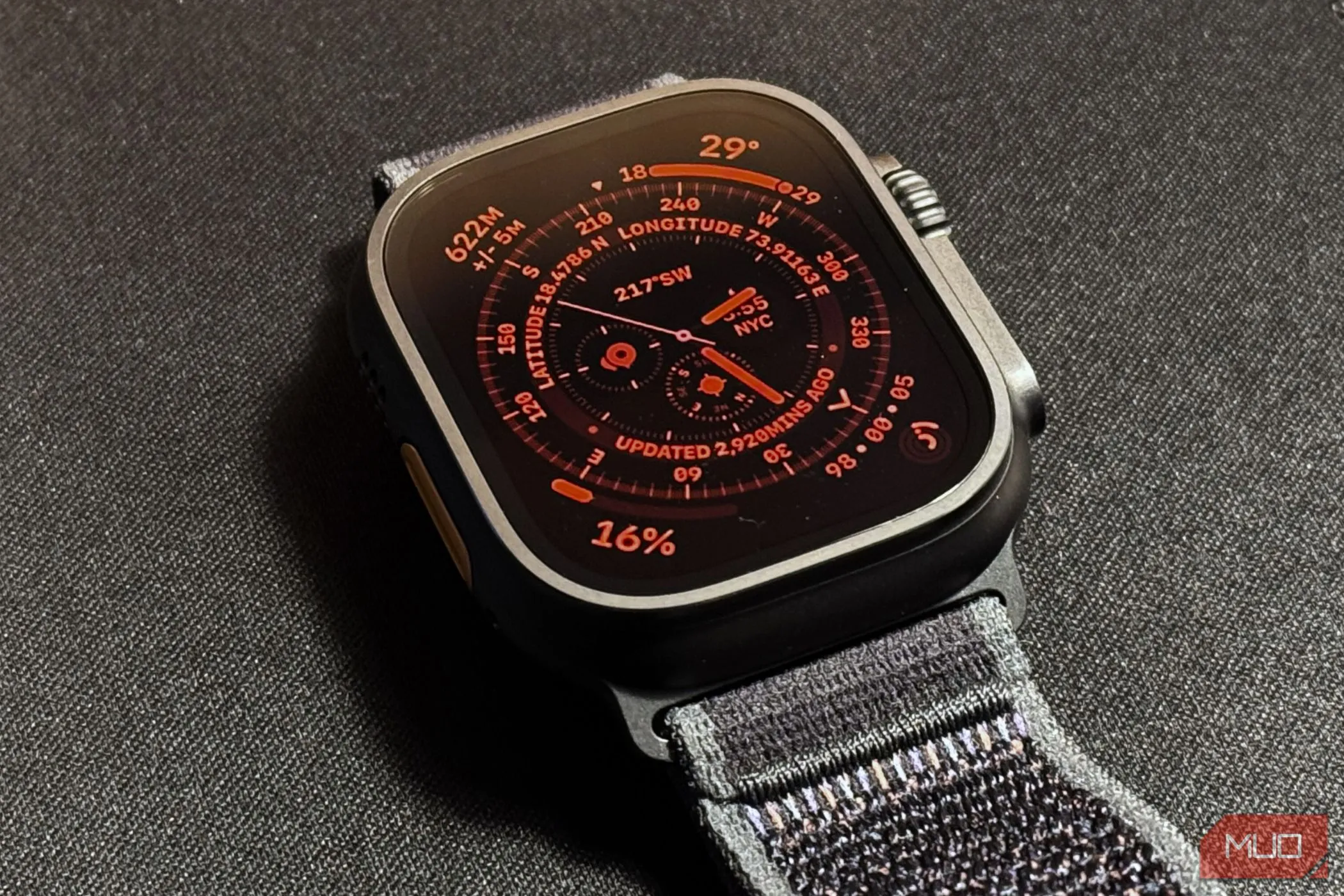 Apple Watch Ultra 2 trên tấm thảm đen với chế độ ban đêm (Night Mode) được kích hoạt hiển thị màu đỏ