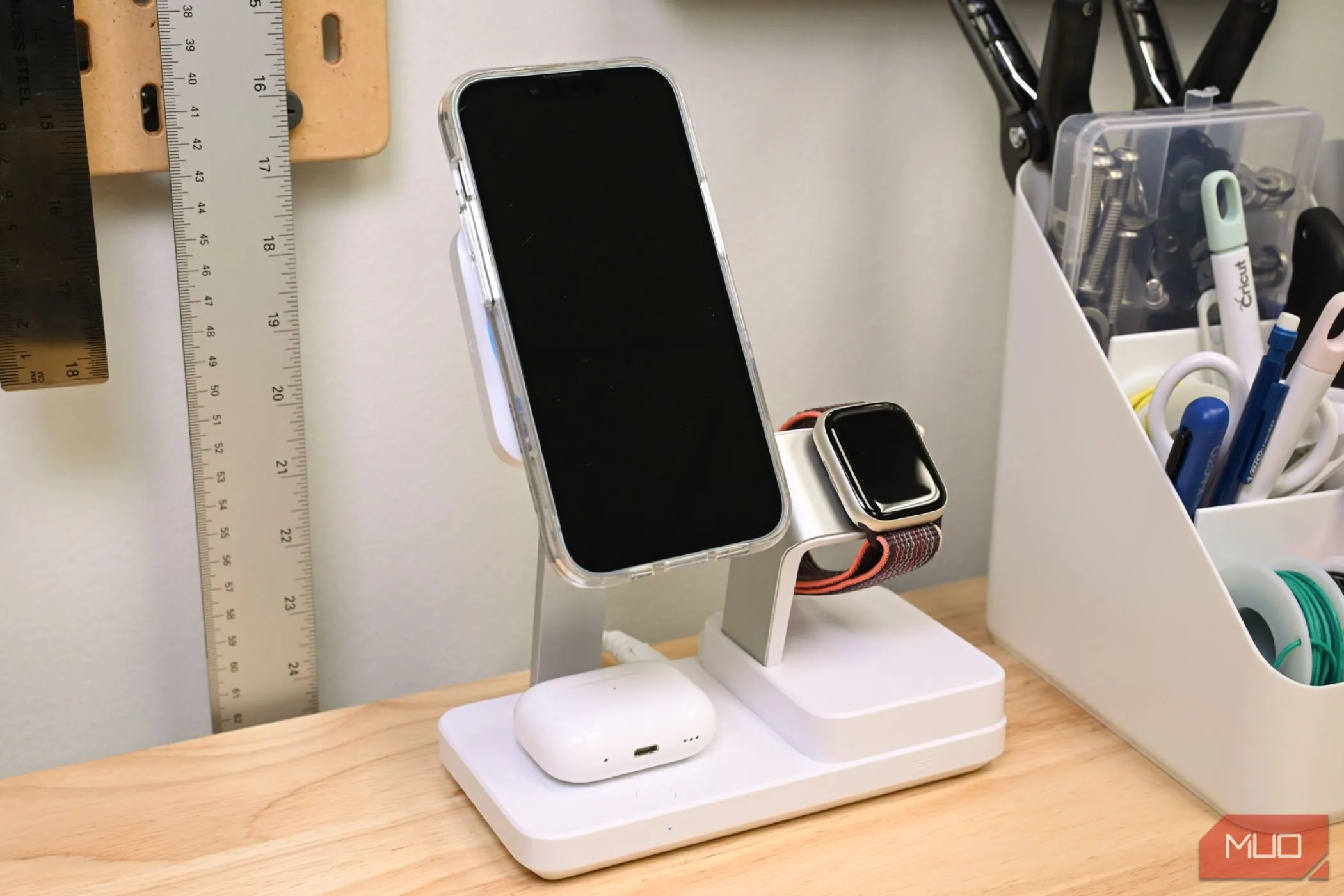 Bộ ba iPhone, AirPods và Apple Watch đang sạc trên đế sạc đa năng ESR 100W 6 trong 1, thể hiện khả năng sạc đồng thời nhiều thiết bị Qi2.
