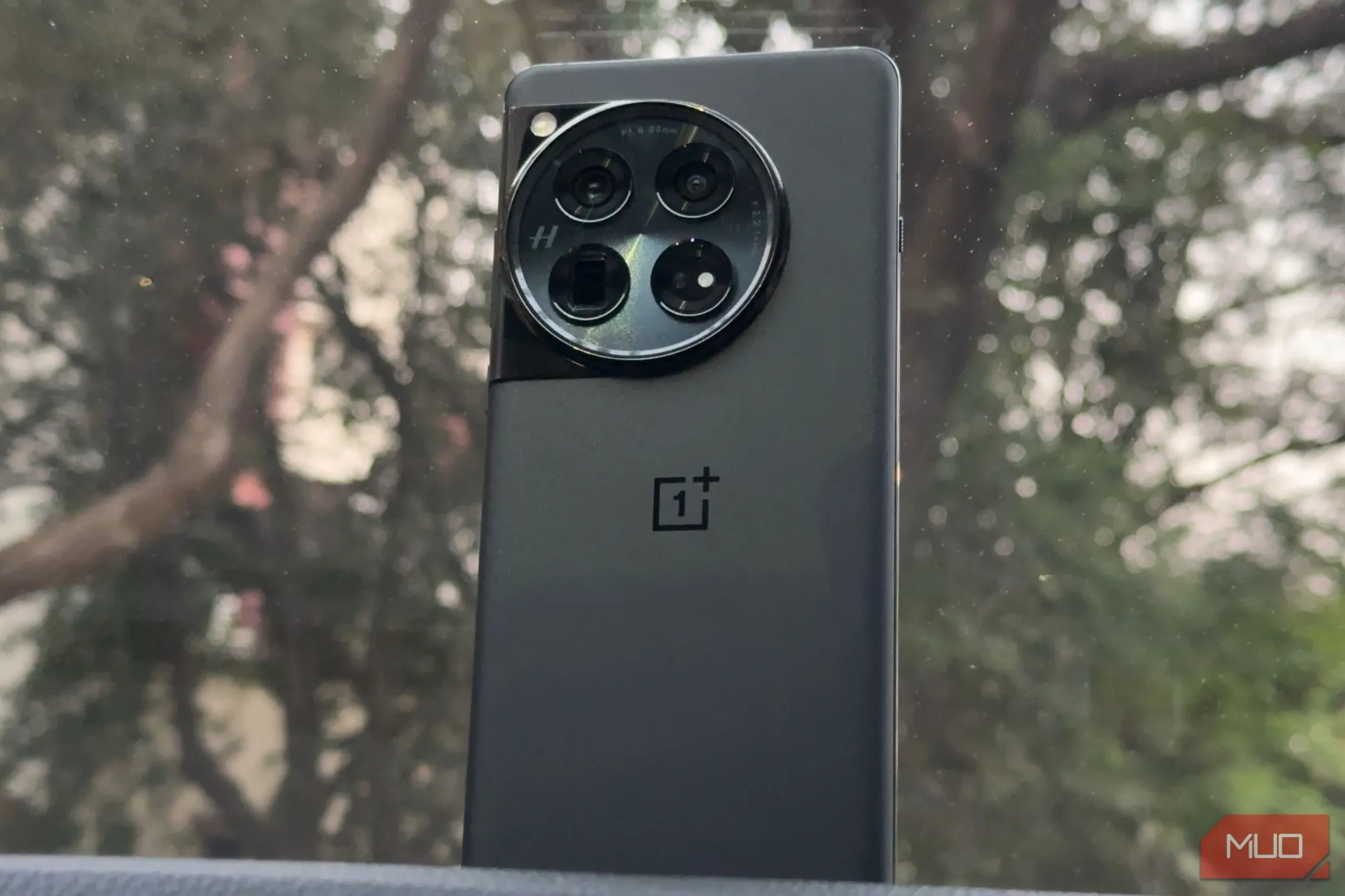 Điện thoại OnePlus 12 màu đen đặt trên bảng điều khiển ô tô, nổi bật thiết kế mặt lưng và sự sang trọng