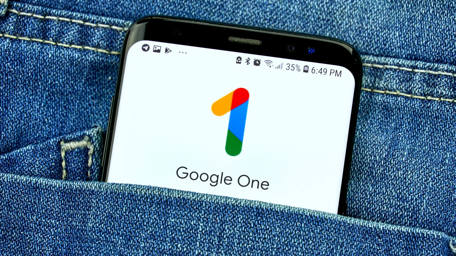 Màn hình điện thoại hiển thị ứng dụng Google One trong túi quần jean, tượng trưng cho dịch vụ lưu trữ đám mây trả phí như một phần của chiến lược sao lưu ảnh toàn diện