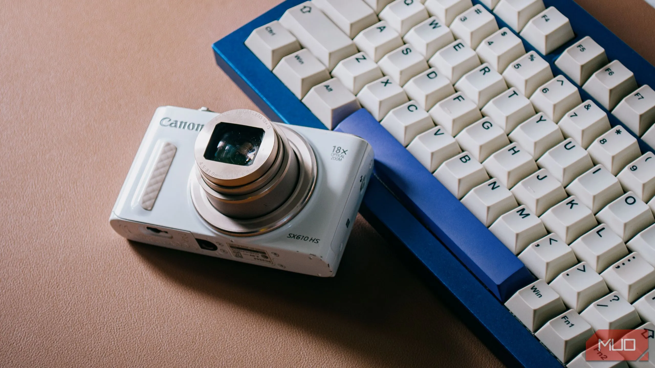 Máy ảnh compact Canon SX610 HS với ống kính kéo dài trên bàn phím, biểu trưng cho sức mạnh nhiếp ảnh di động