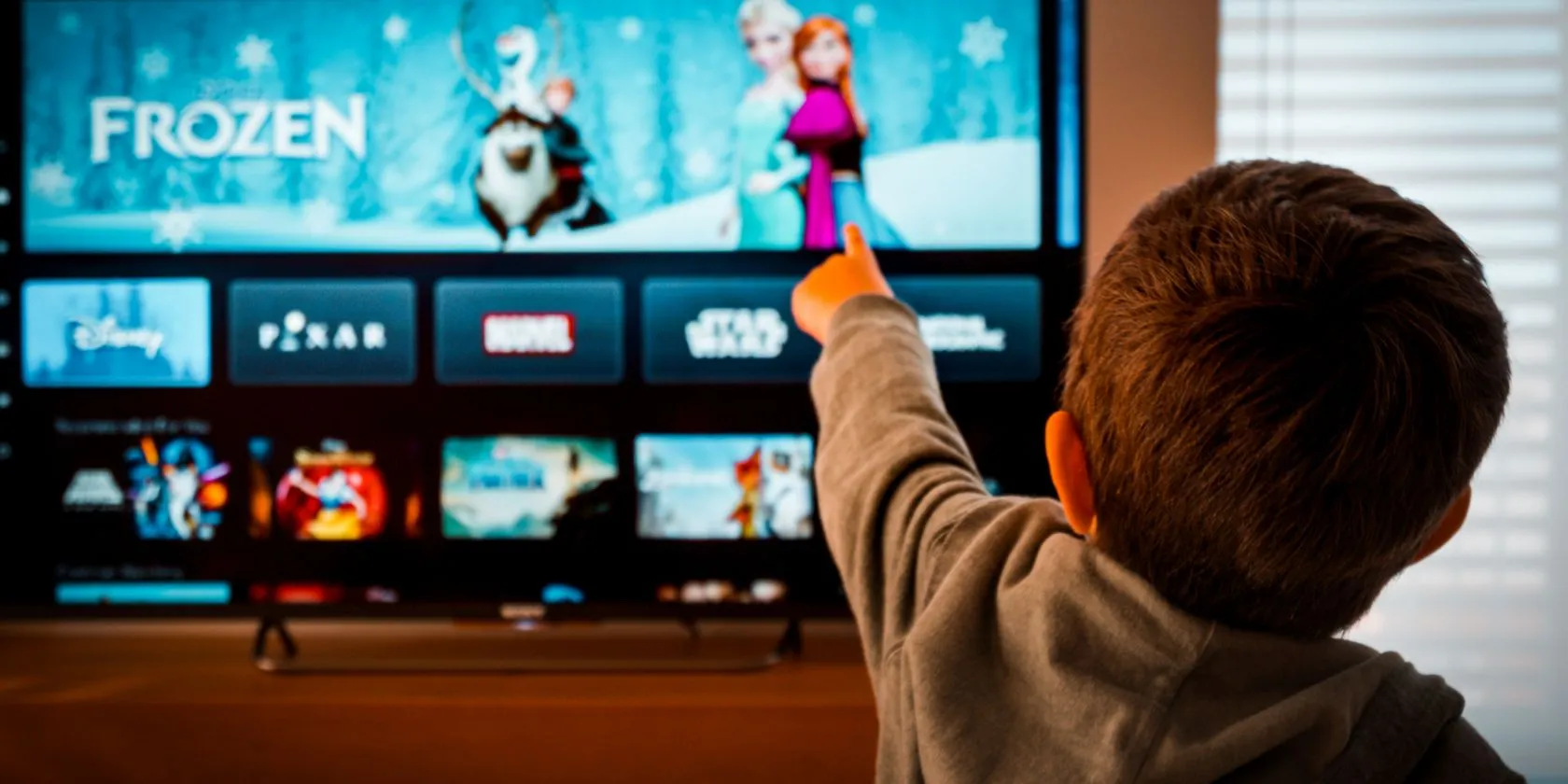 Một bé gái đang chỉ vào biểu tượng Disney+ trên màn hình TV