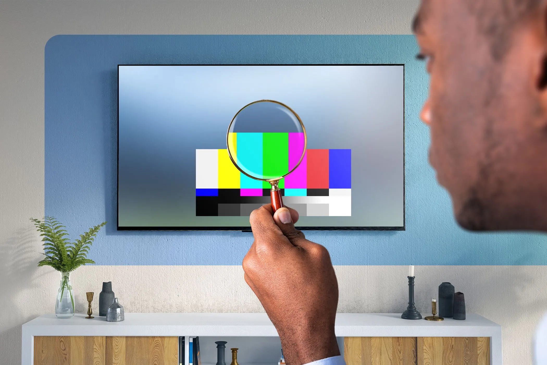 Một người đàn ông đang nhìn chăm chú vào TV qua một chiếc kính lúp, như đang kiểm tra chi tiết hình ảnh