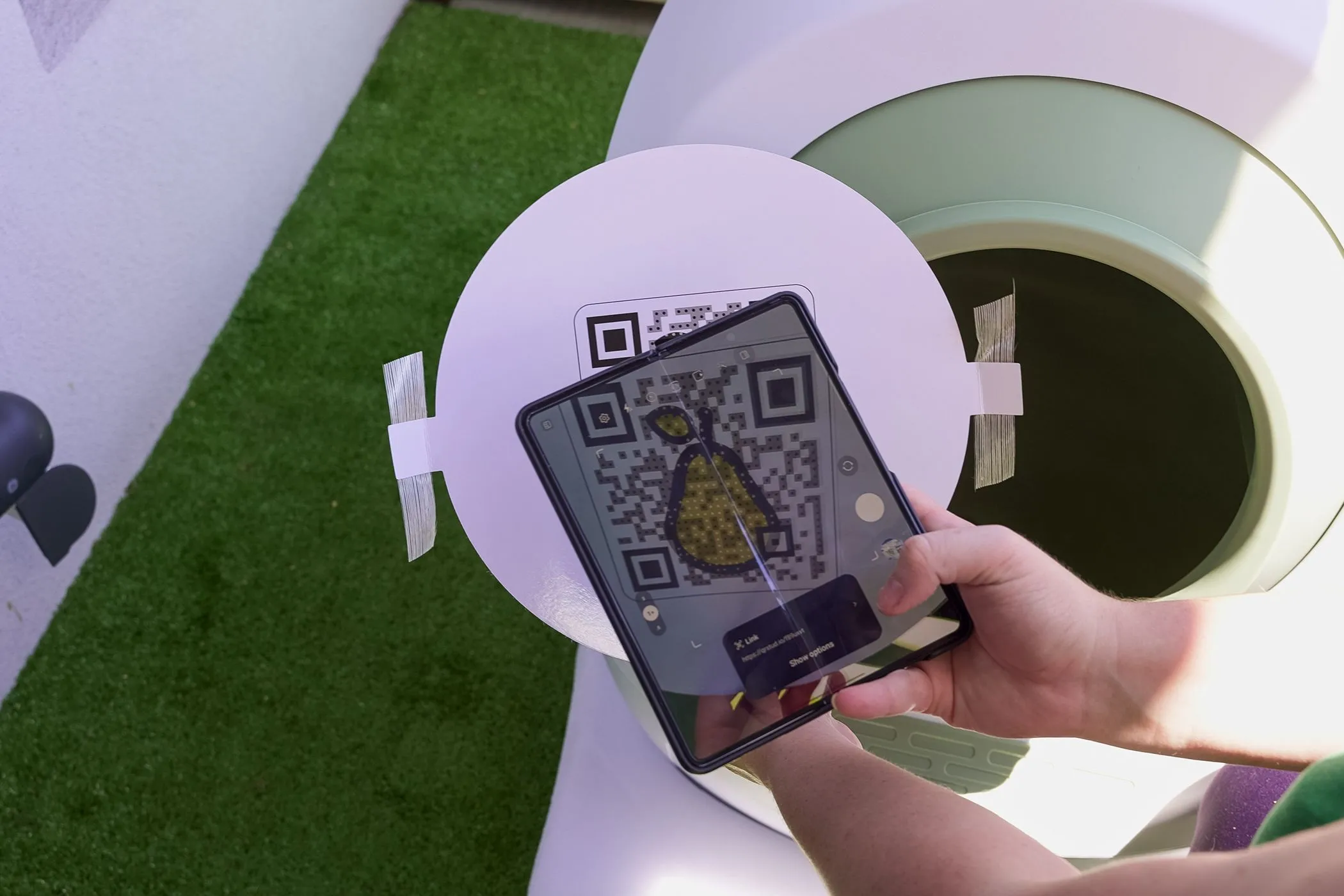 Một người đàn ông đang sử dụng điện thoại quét mã QR dán trên tường, minh họa việc tương tác với mã trong ngữ cảnh công cộng.
