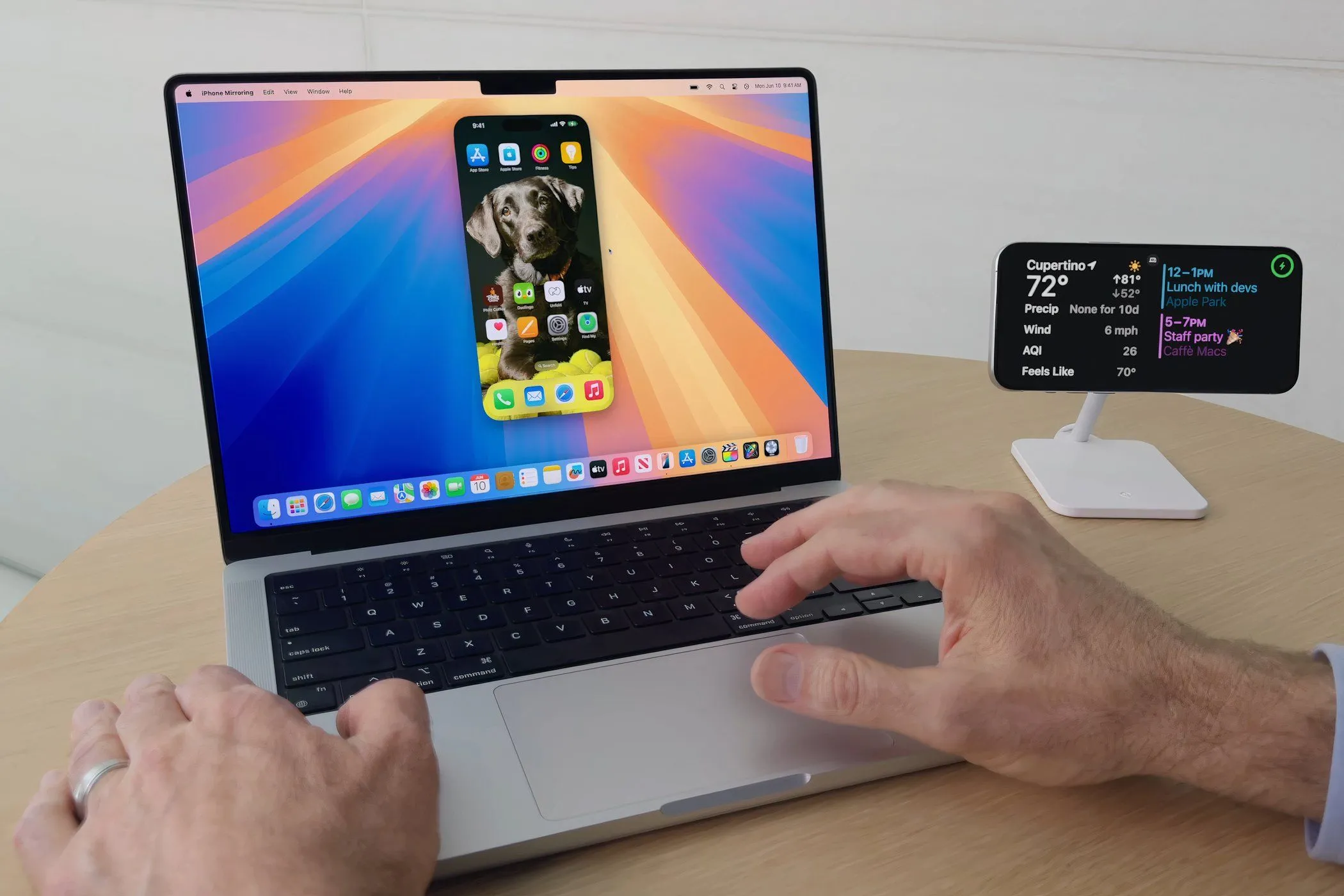 Một người đàn ông điều khiển iPhone trực tiếp từ MacBook Pro chạy macOS Sequoia với tính năng iPhone Mirroring.