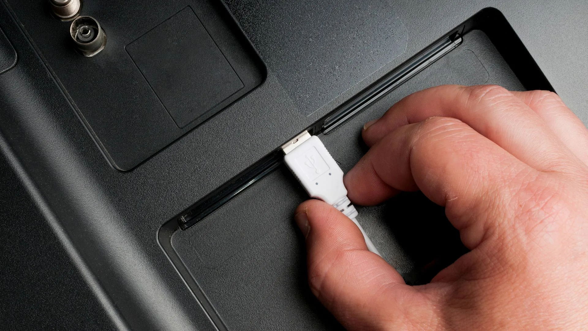 Người đàn ông cắm cáp USB vào cổng phía sau TV