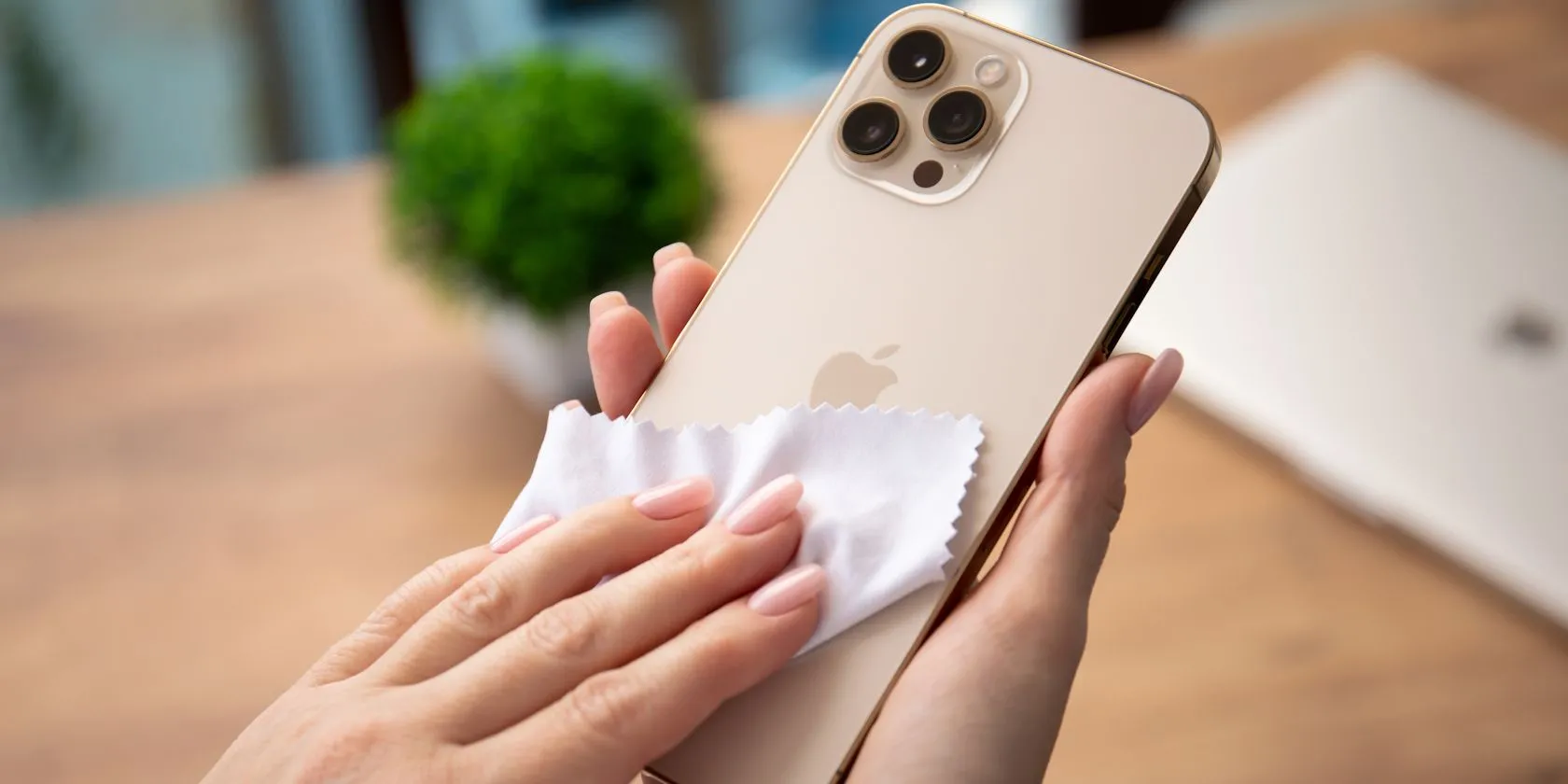 Người phụ nữ đang dùng khăn microfiber để vệ sinh màn hình điện thoại iPhone