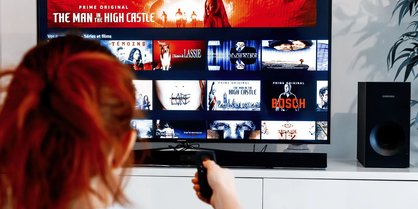 Người phụ nữ điều khiển remote chỉ vào màn hình TV hiển thị giao diện của Amazon Prime Video