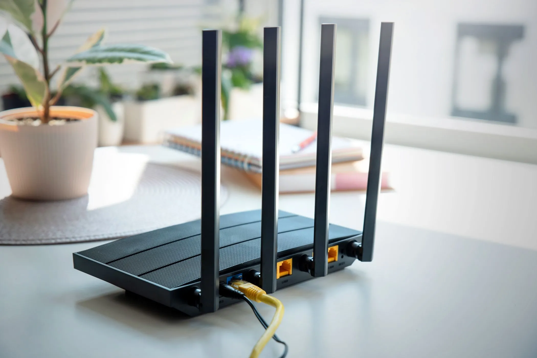 Router Wi-Fi bốn ăng-ten đặt trên bàn, tượng trưng cho việc quản lý và cấu hình nâng cao để tăng cường hiệu suất và an ninh mạng.