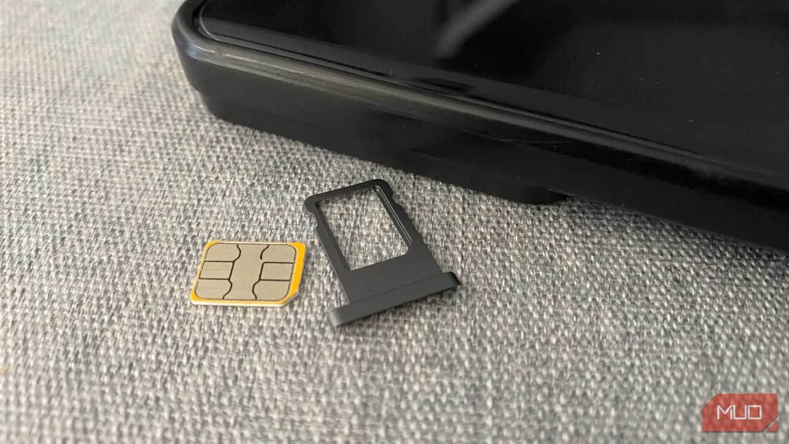Thẻ SIM vật lý và khay đựng đặt cạnh điện thoại di động, tượng trưng cho lựa chọn kết nối địa phương.