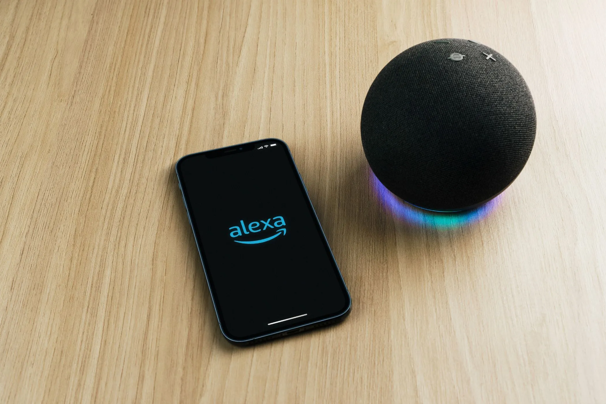 Ứng dụng Alexa trên điện thoại thông minh đặt cạnh loa Amazon Echo, minh họa sự kết nối giữa thiết bị và phần mềm
