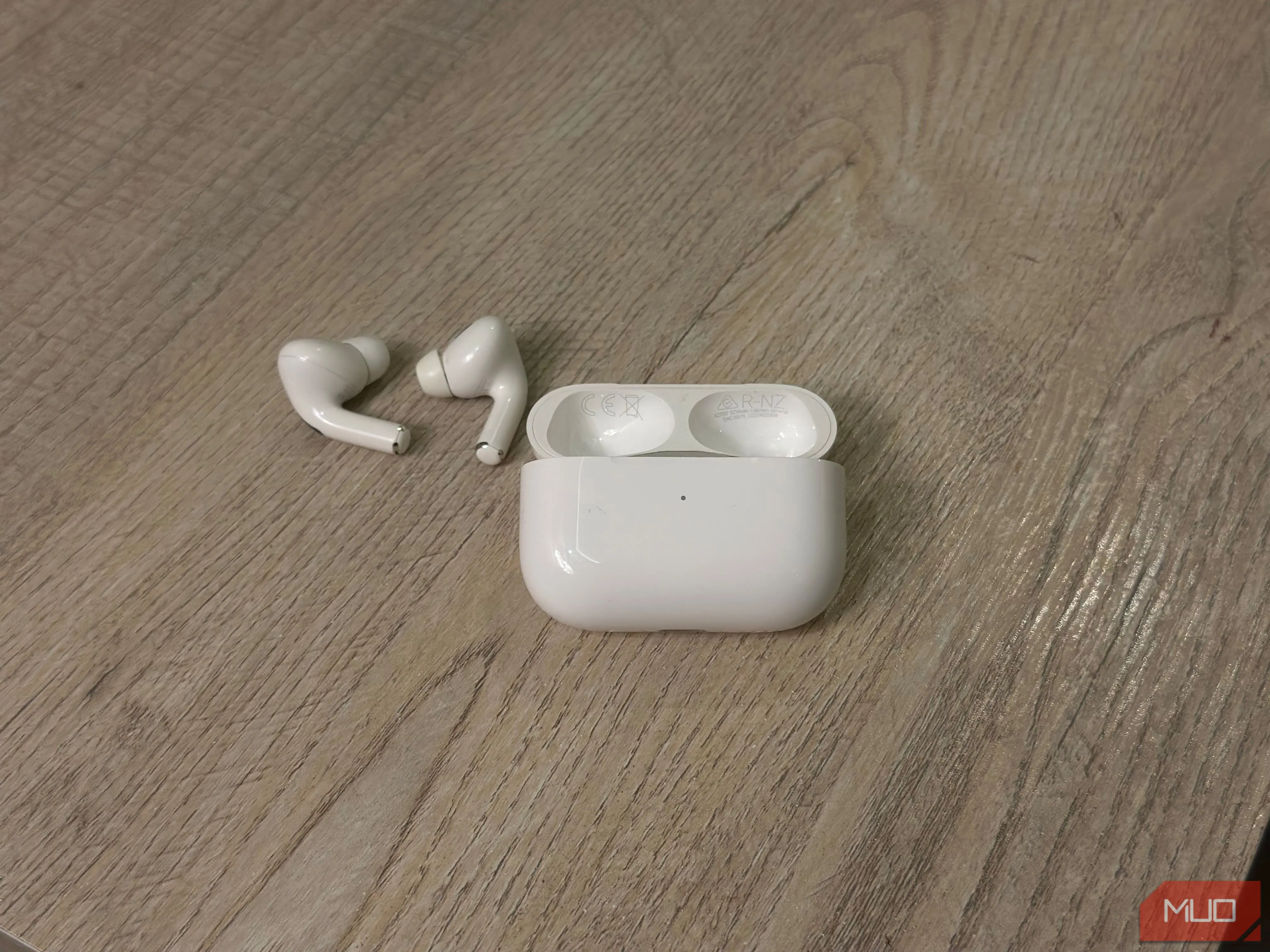 Vỏ sạc AirPods mở nắp và tai nghe bên trong, cho thấy vị trí số kiểu máy và số serial được in trên nắp.